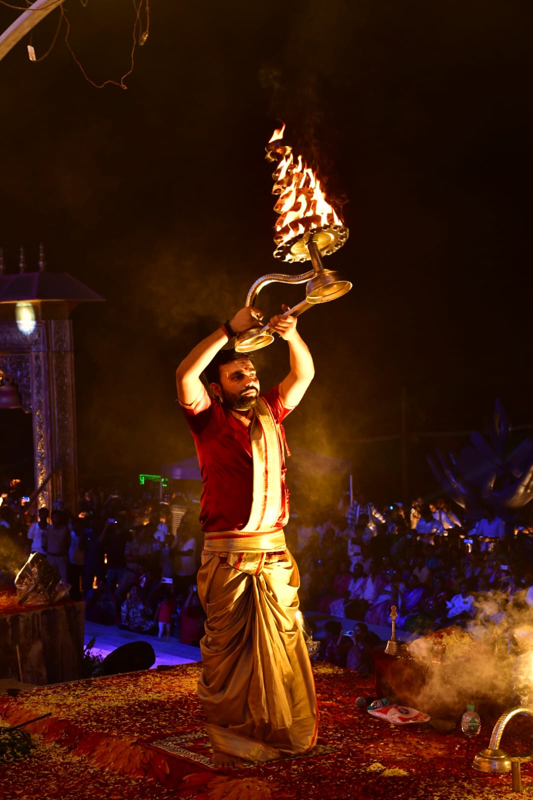 Priest performing Ganga Aarti with multi-tier brass lamp